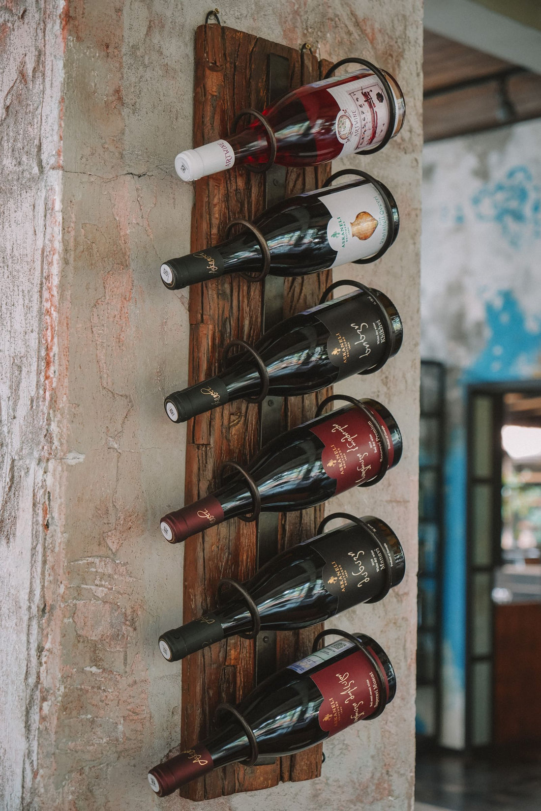 Porte-bouteilles mural en bois vieilli, plusieurs bouteilles couchées sur un mur