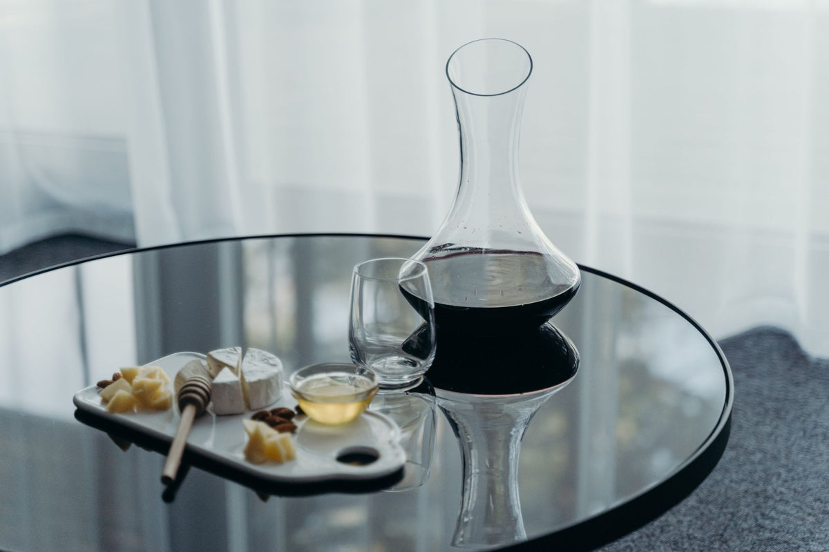 Carafe de vin rouge sur une table noire avec fromages