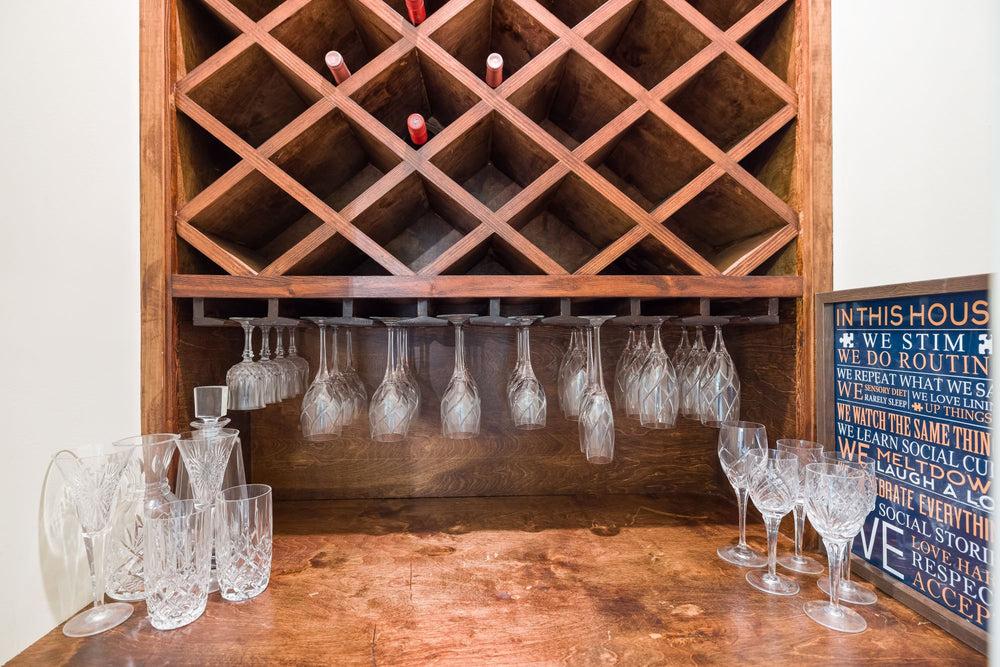 Casier à bouteilles en bois avec verres suspendus et carafes en cristal