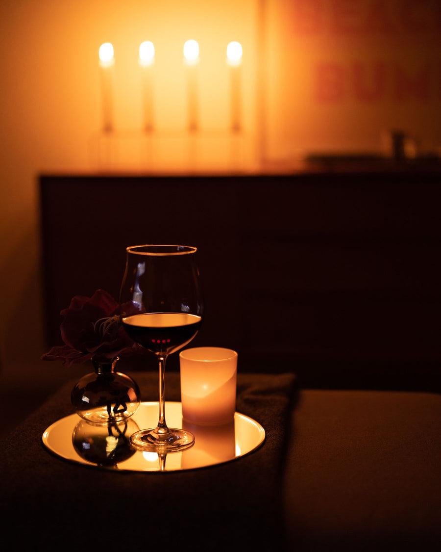 Un verre de vin rouge et une bougie, dans la lumière chaude du soir