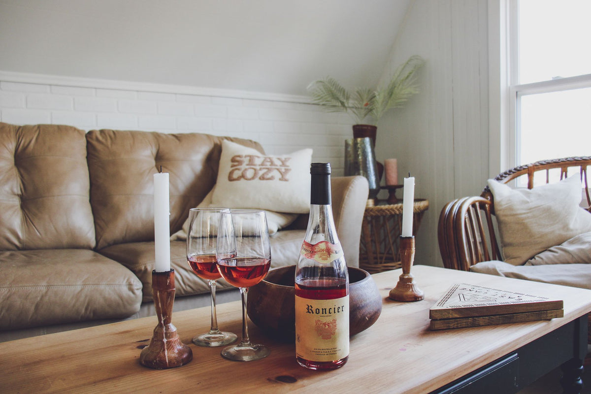 Bouteille de vin, deux verres et bougies sur une table basse devant un canapé